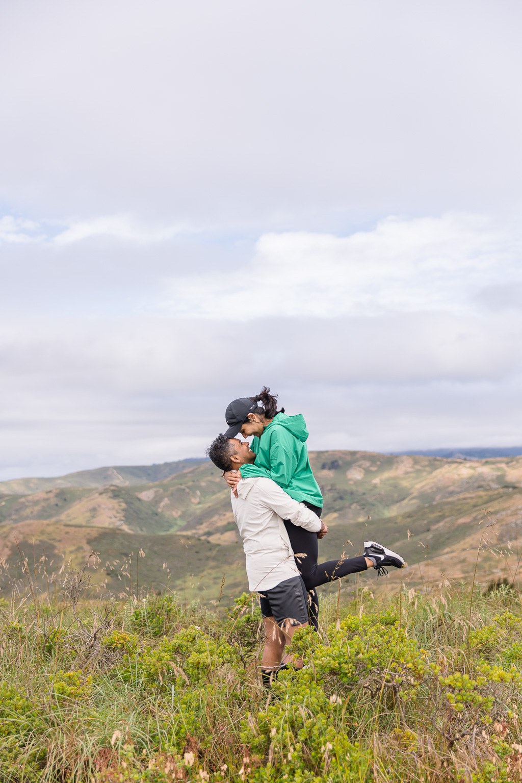 photo of couple lifting up in the hills