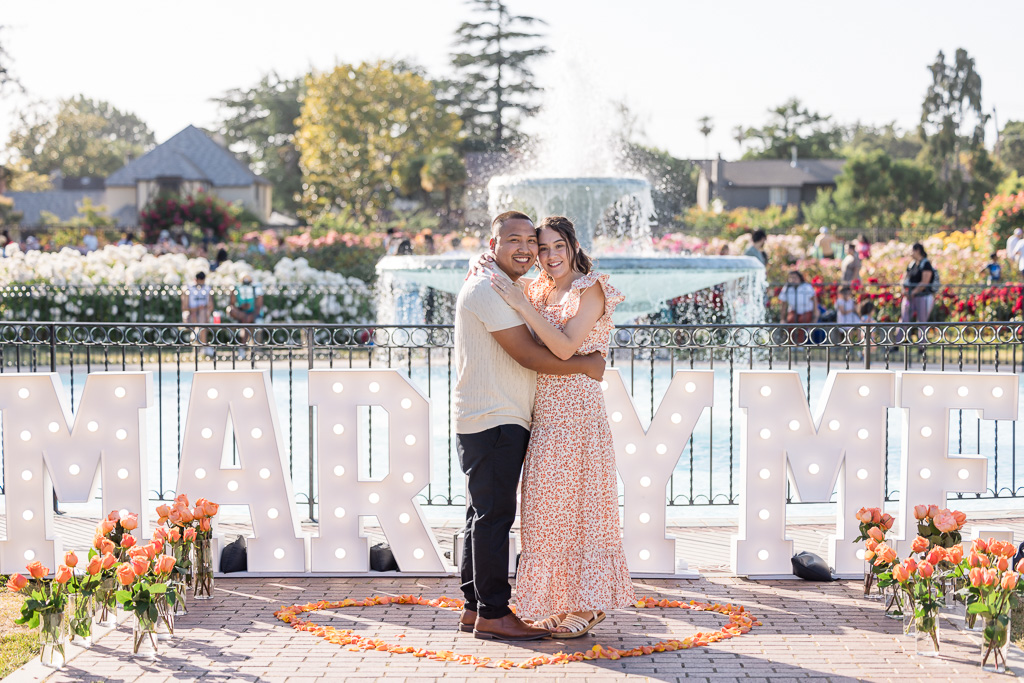 newly-engaged couple standing in front of proposal decor/setup