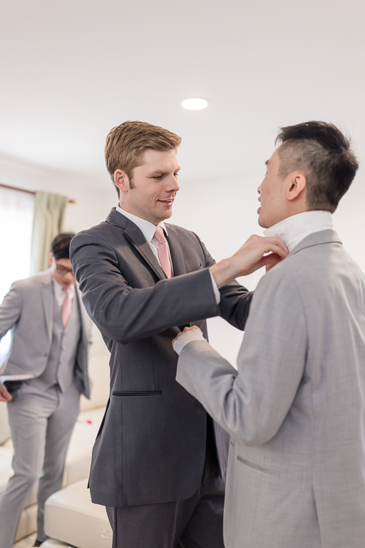 groom helping groomsman with his tie