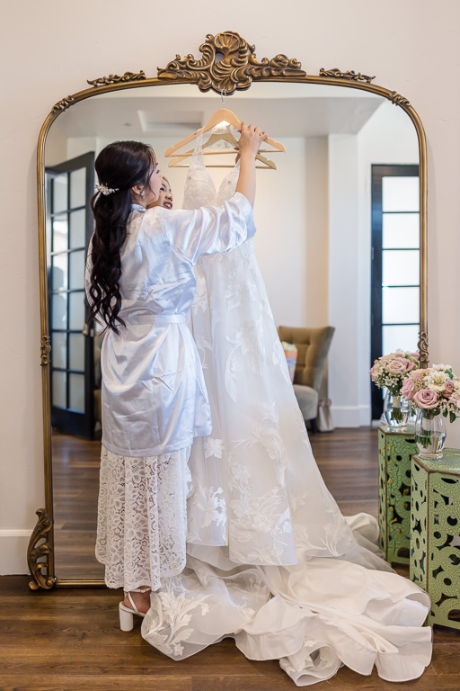 bride hanging her dress on a mirror