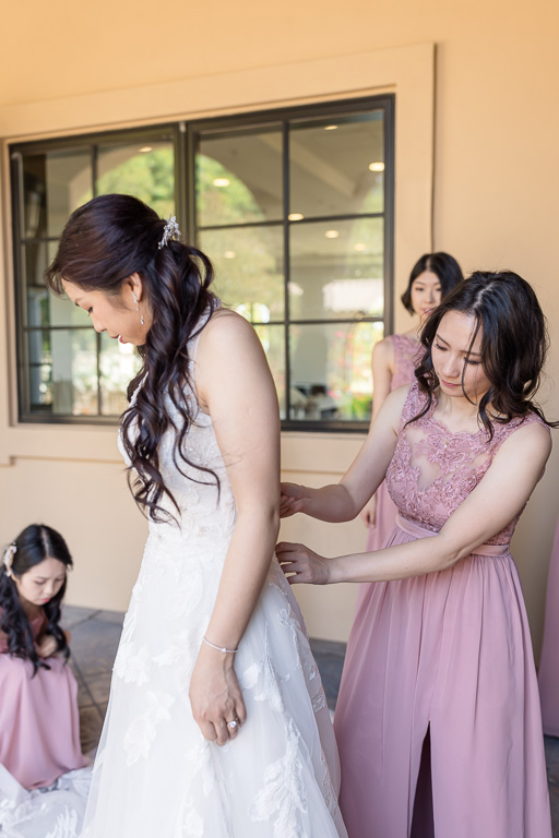bride getting her dress on with help from bridesmaids