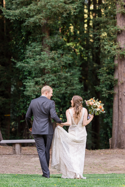 bride and groom casually walking into the woods