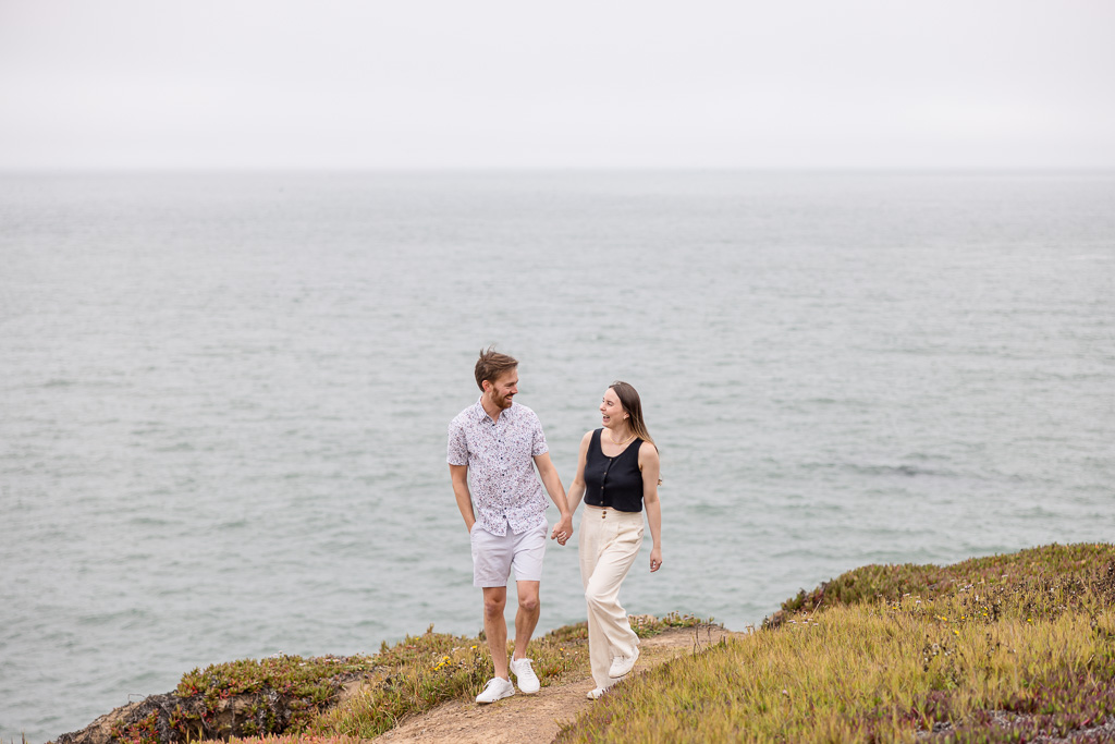 cute couple walking by the ocean on top of cliffside