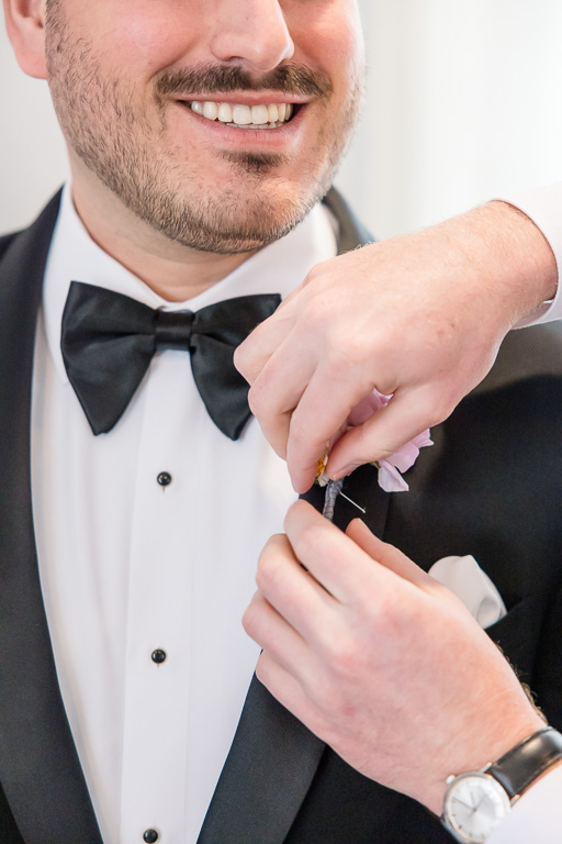 pinning boutonniere onto the groom