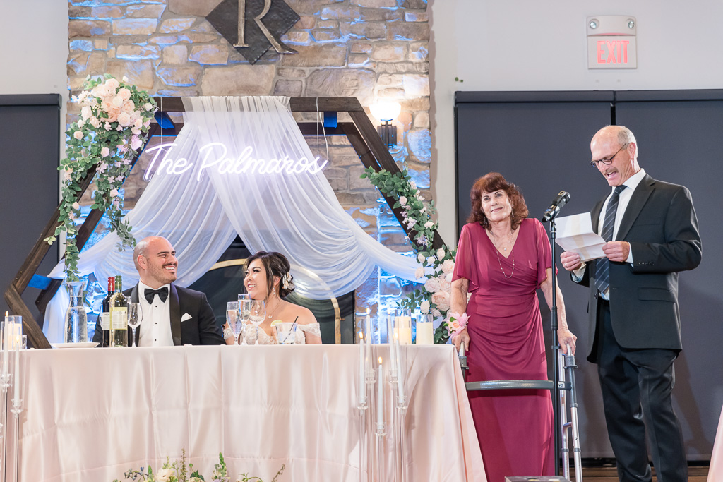 groom's parents giving a dinner toast at the sweetheart table