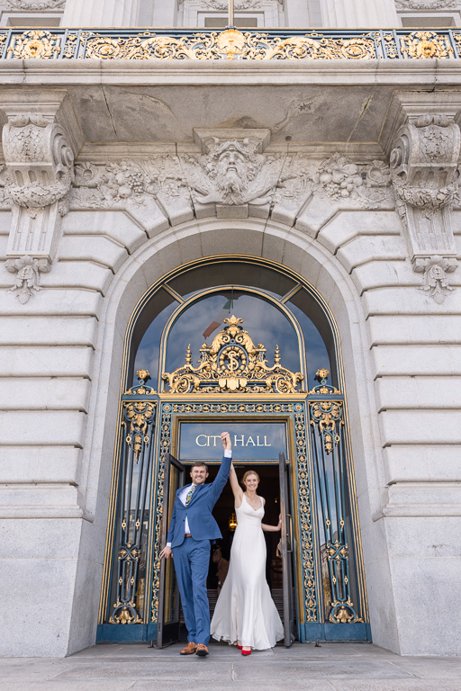bride and groom exiting San Francisco City Hall front door