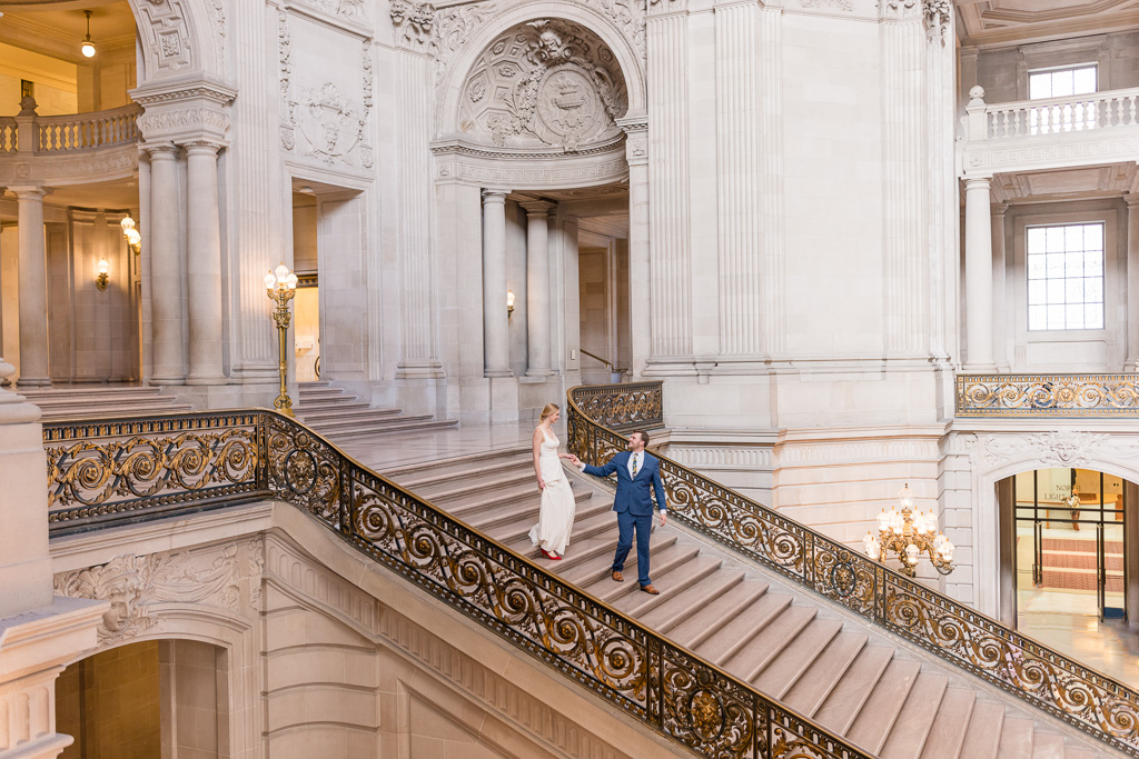 bride and groom walking down the grand staircase at City Hall