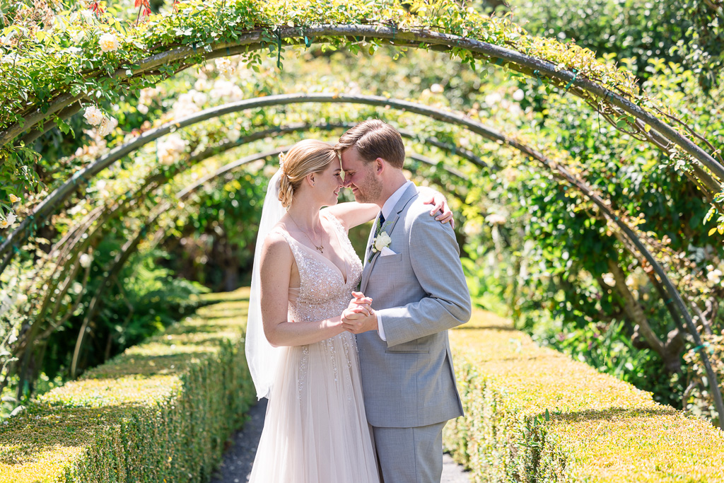 beautiful portrait of wedding couple under lush plant arch