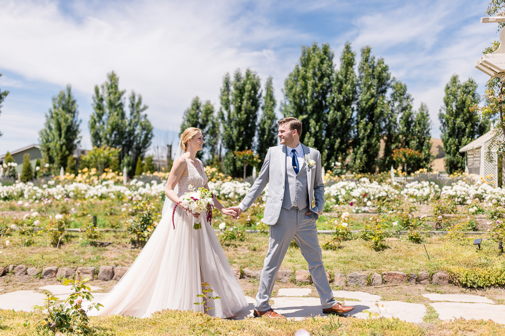 bride and groom walking through a rose garden