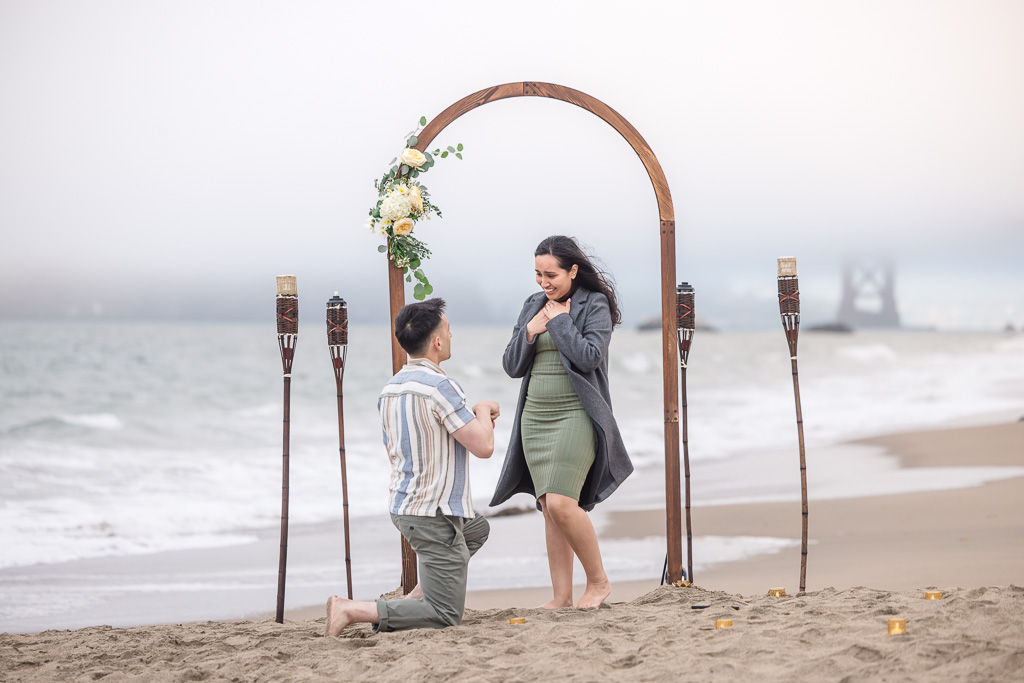 Baker Beach surprise proposal with DIY wooden floral arch and tiki torches