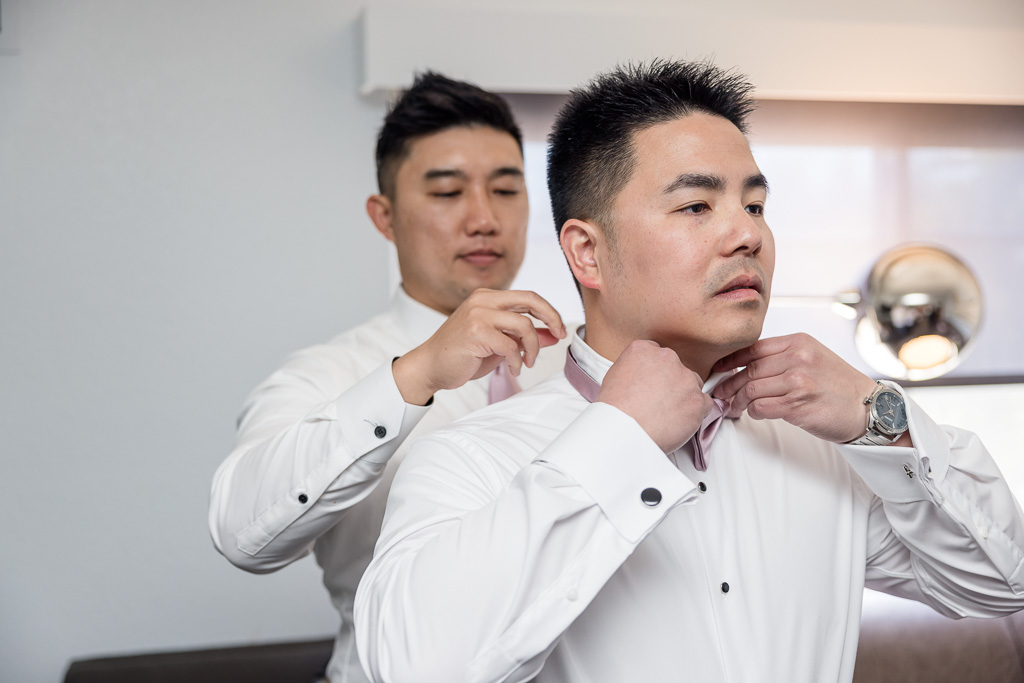 groomsman helping groom with bow tie