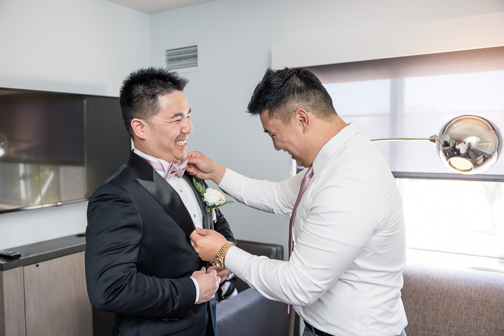 cute moment between groom and groomsman while getting dressed