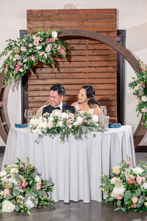 newlyweds at sweetheart table during reception