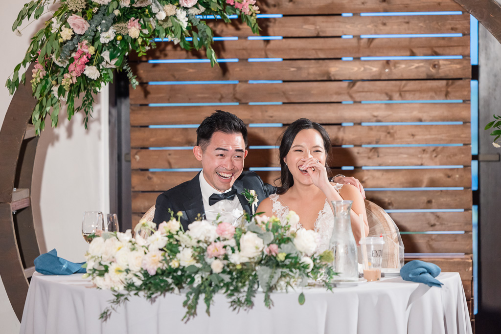 bride and groom at the sweetheart table laughing