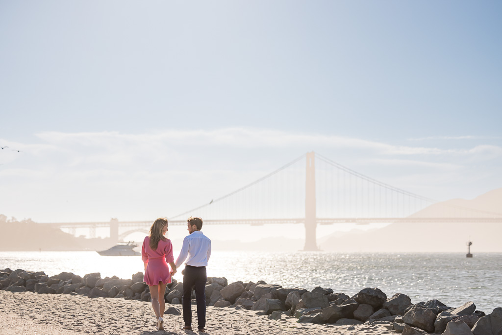 couple walking towards the Golden Gate Bridge on a sandy path
