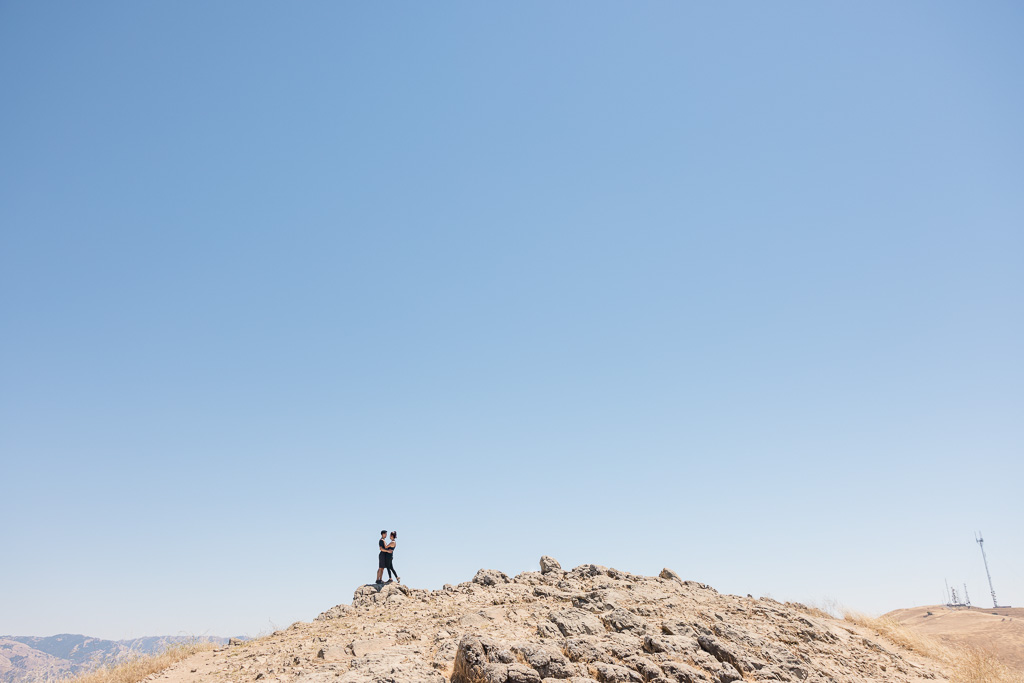 engagement shoot of couple on mountaintop off in the distance
