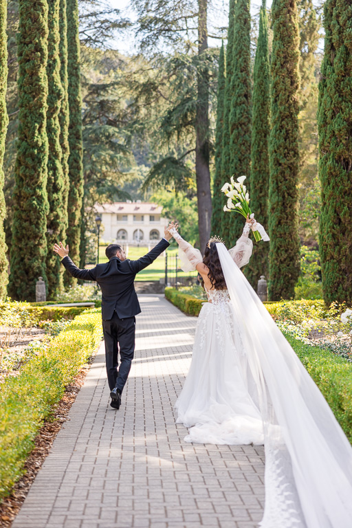 newlyweds walk down the long aisle surrounded by tall trees