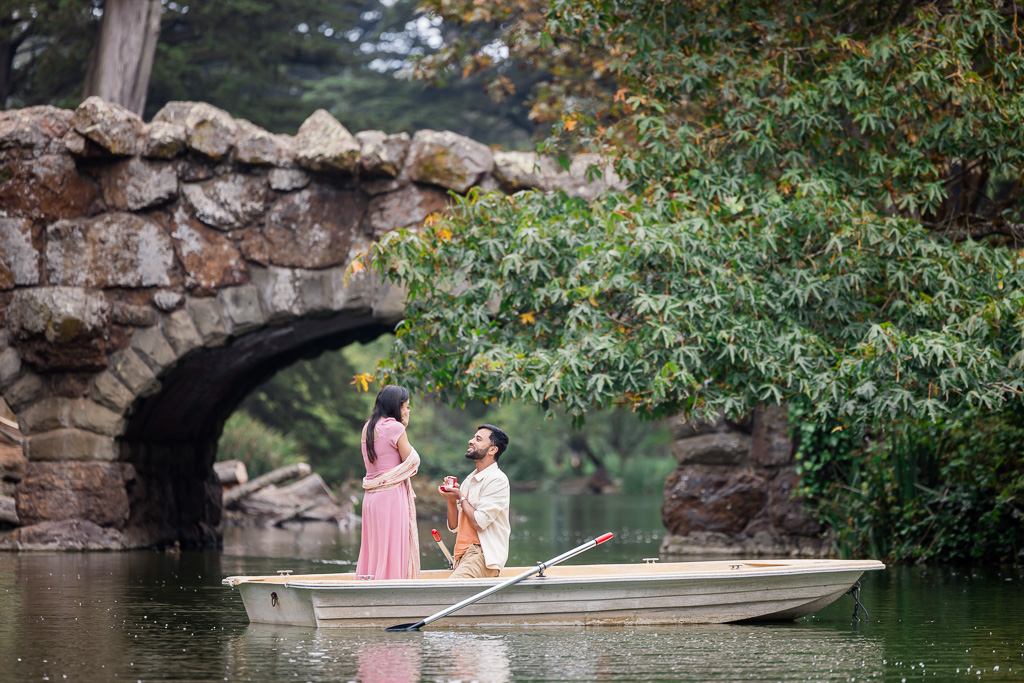 rowboat on a lake surprise proposal with a stone arch bridge in the background
