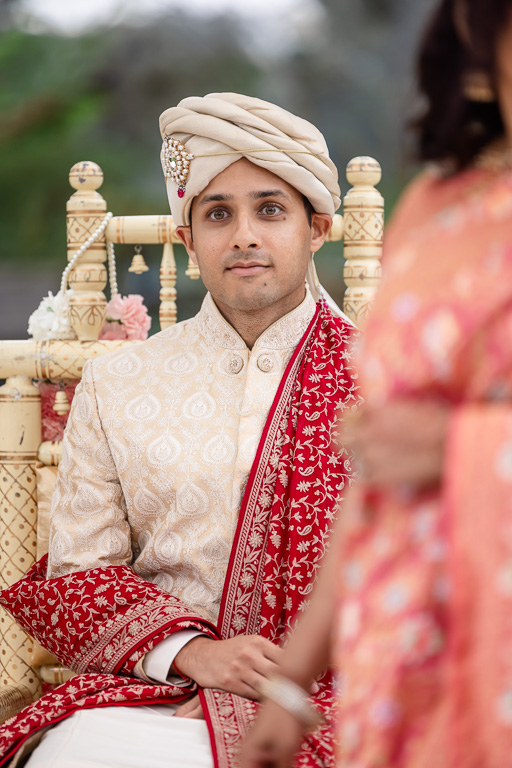Indian groom under mandap watching bride approach