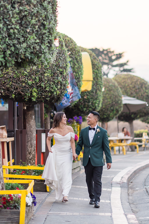 candid wedding portrait of bride and groom walking on sidewalk next to shops