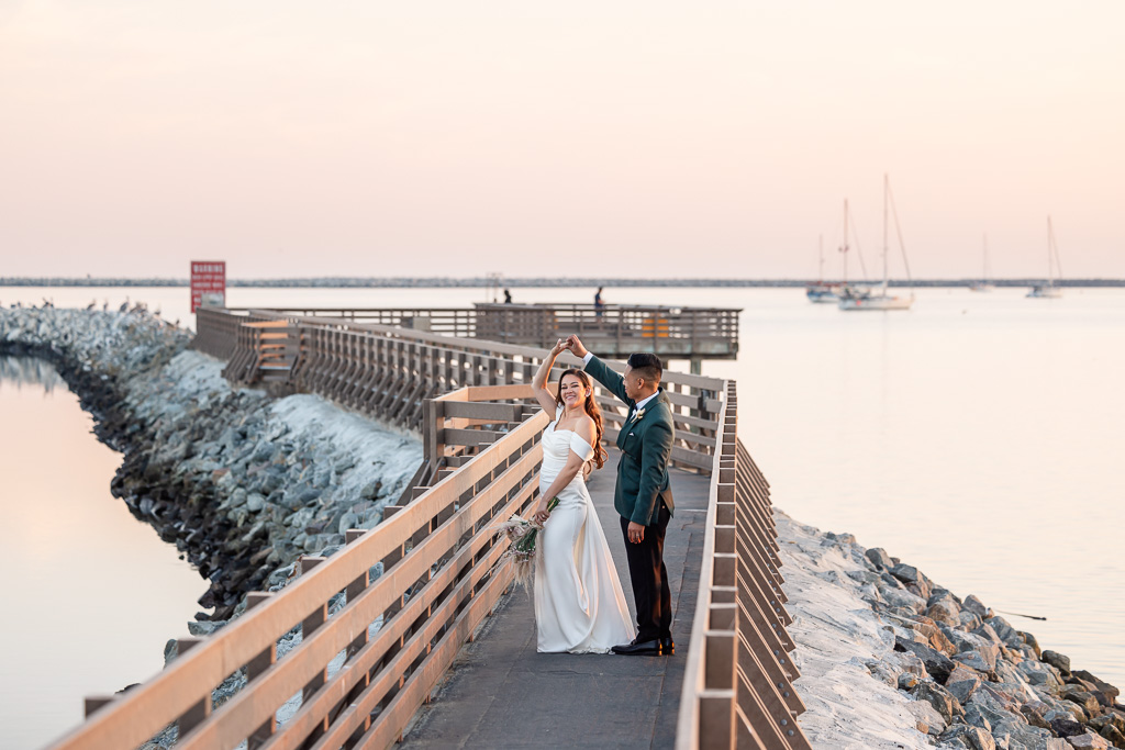 photo of bride and groom dancing on an ocean pier at sunset