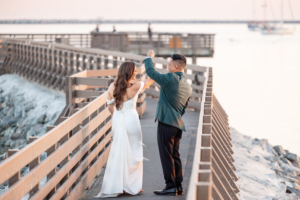 bride and groom dancing on a pier at sunset