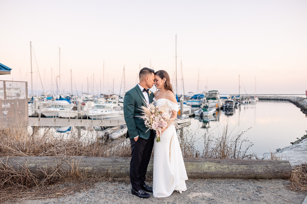 portrait of groom and bride in front of marina with sailboats