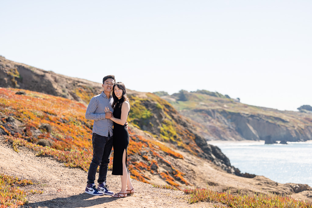 newly engaged couple posing up on the cliff above Rodeo Beach