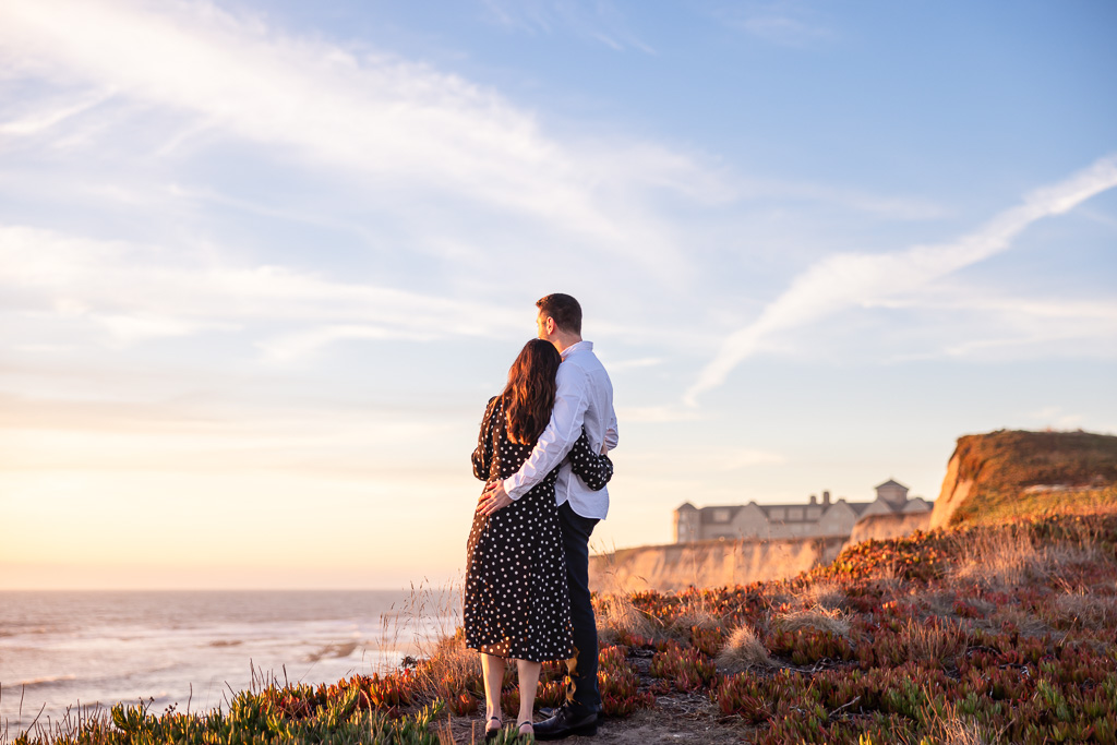 couple looking off into the sunset on an ocean cliffside in Half Moon Bay