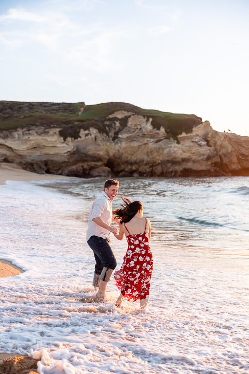 playfully romping in the ocean for engagement photos