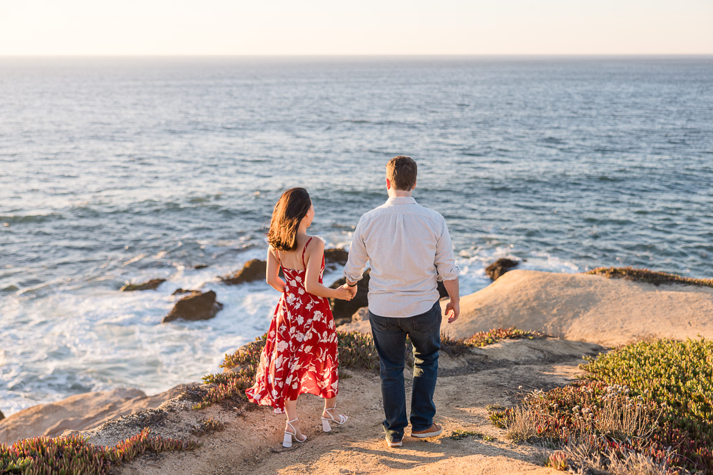 couple looking off into the sunset from an ocean cliff