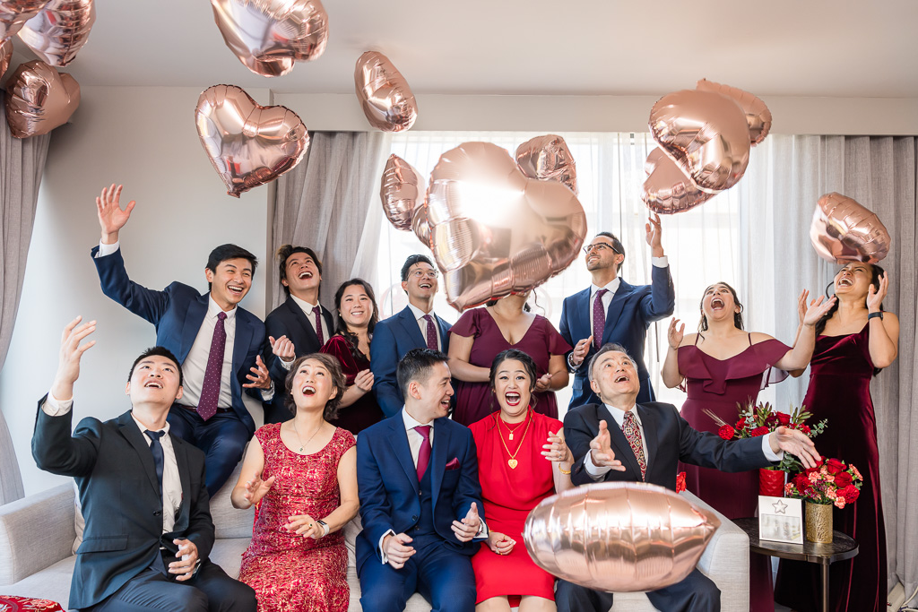 fun photo of wedding party throwing heart-shaped balloons in a hotel room