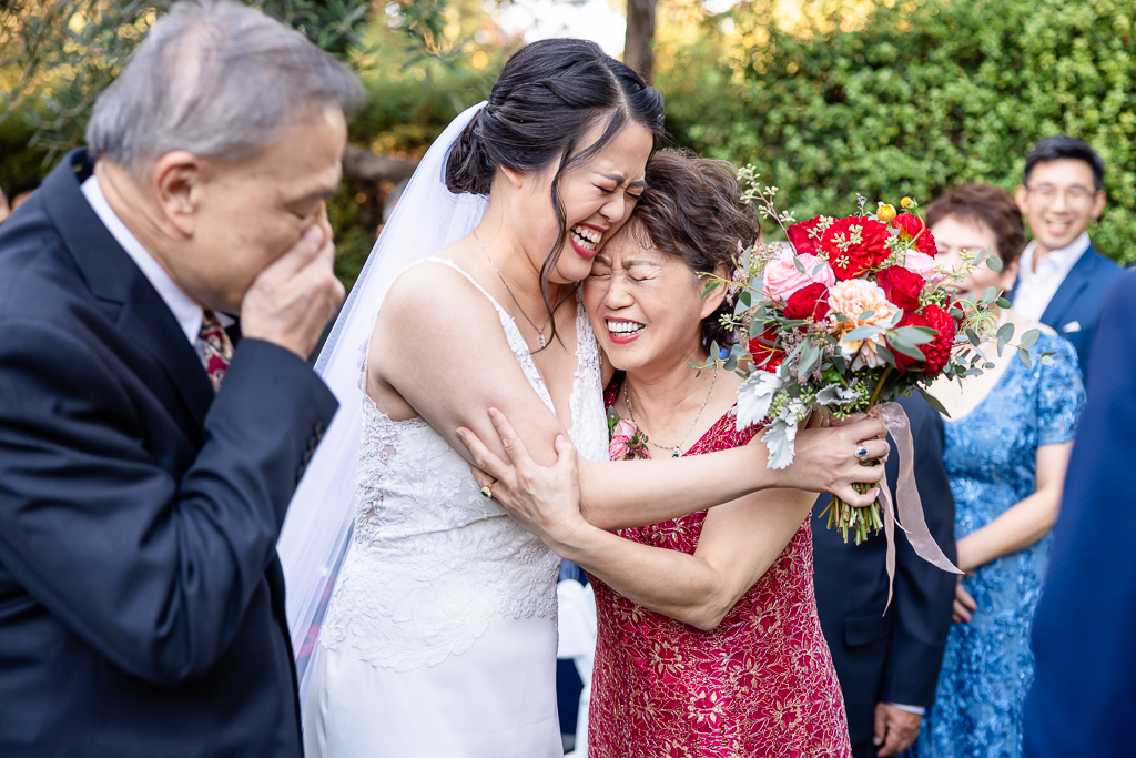 emotional moment between bride and parents at the end of the aisle