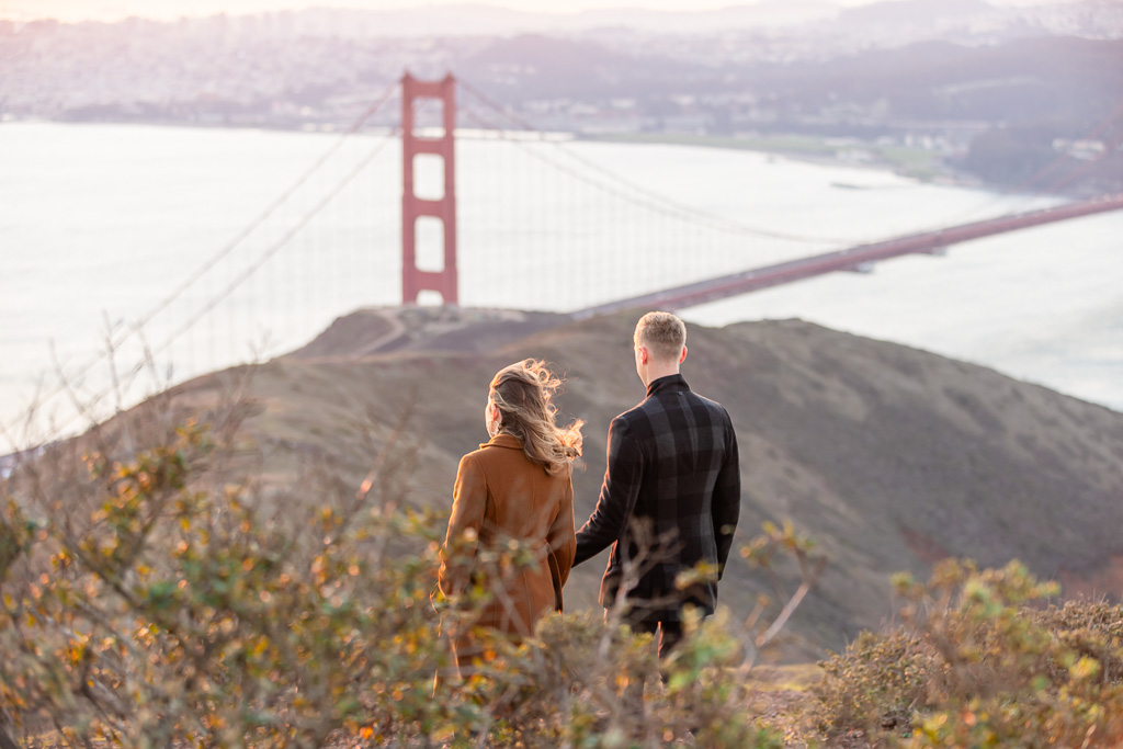 couple standing on a hill looking at the Golden Gate Bridge