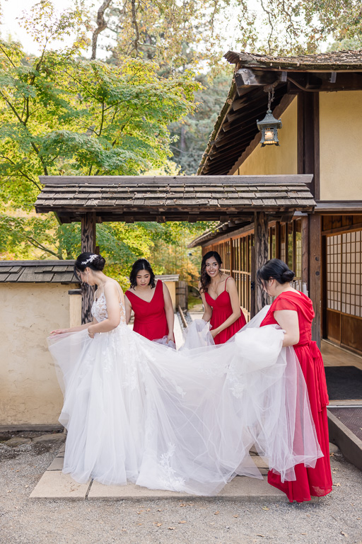 bridesmaids spreading the bride's dress outdoors at Hakone Gardens