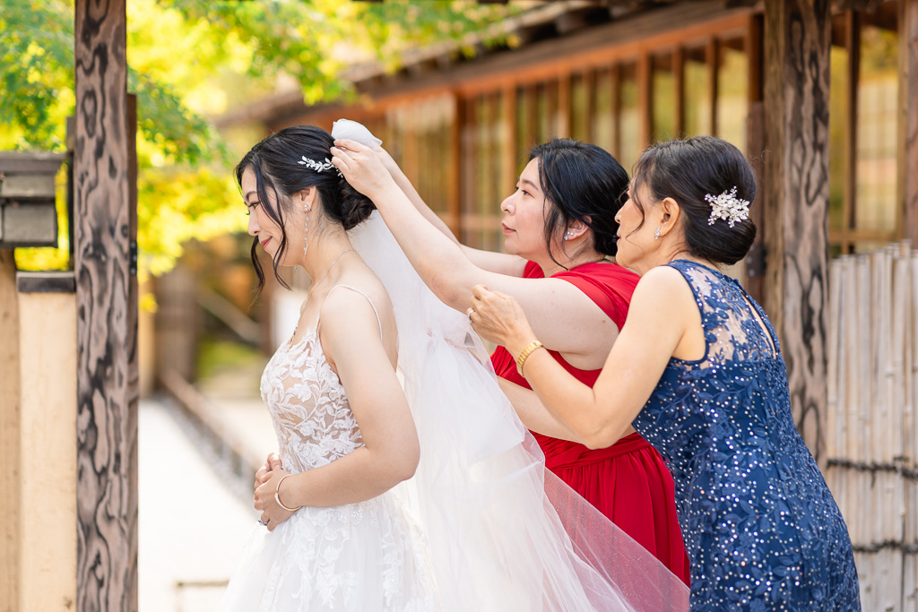 bridesmaids and mom helping bride with her hairpiece