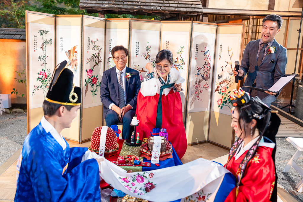 parents tossing chestnuts and dates onto cloth held by bride and groom during Korean tea ceremony