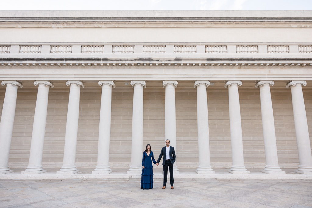 wide angle portrait of a couple in front of white marble columns