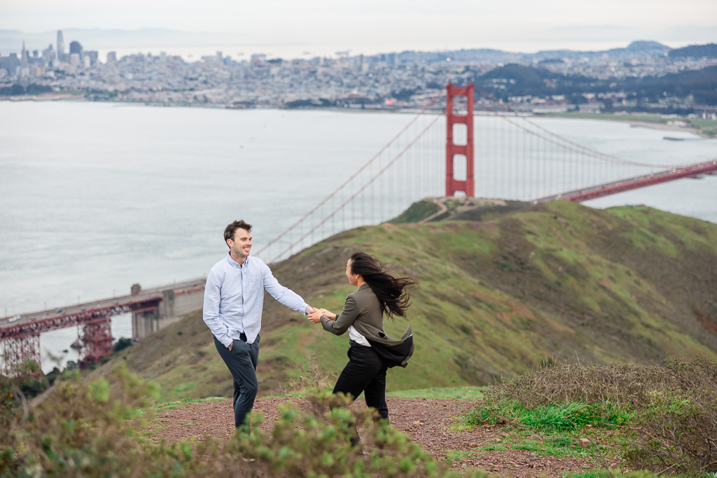 couple standing on top of a tall hill overlooking San Francisco