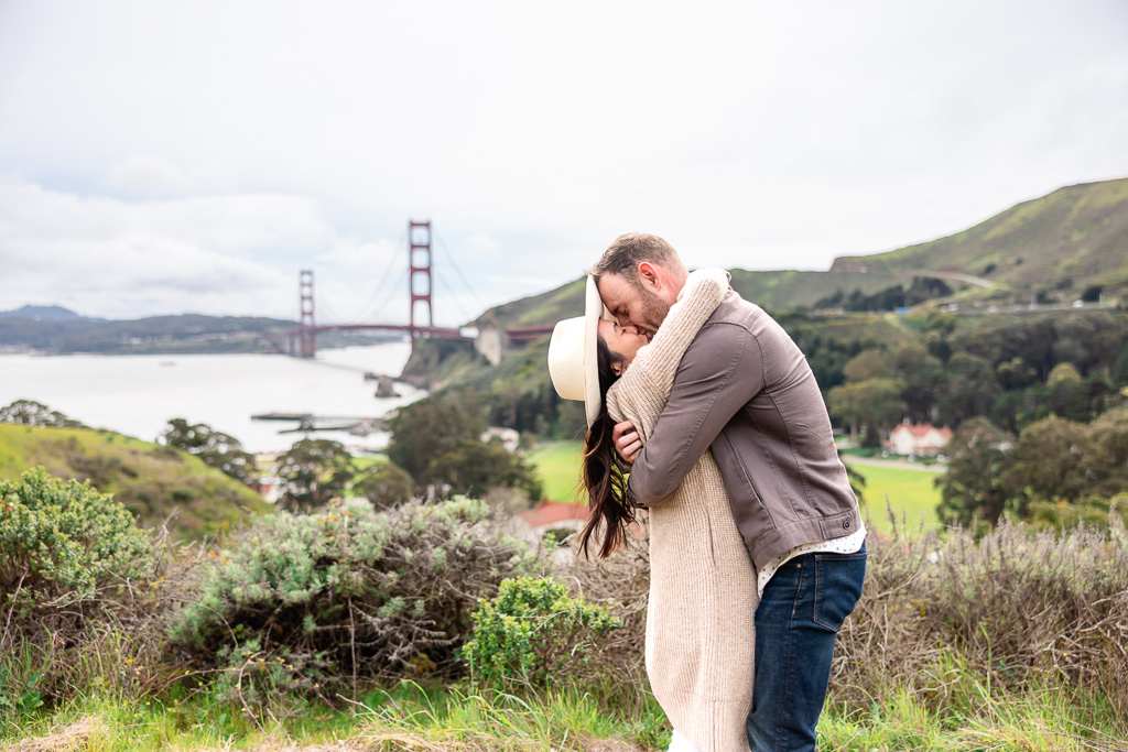 a kiss on a trail overlooking the Golden Gate Bridge