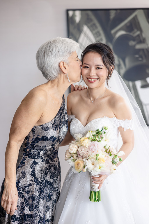 mother-in-law giving bride a kiss on the cheek