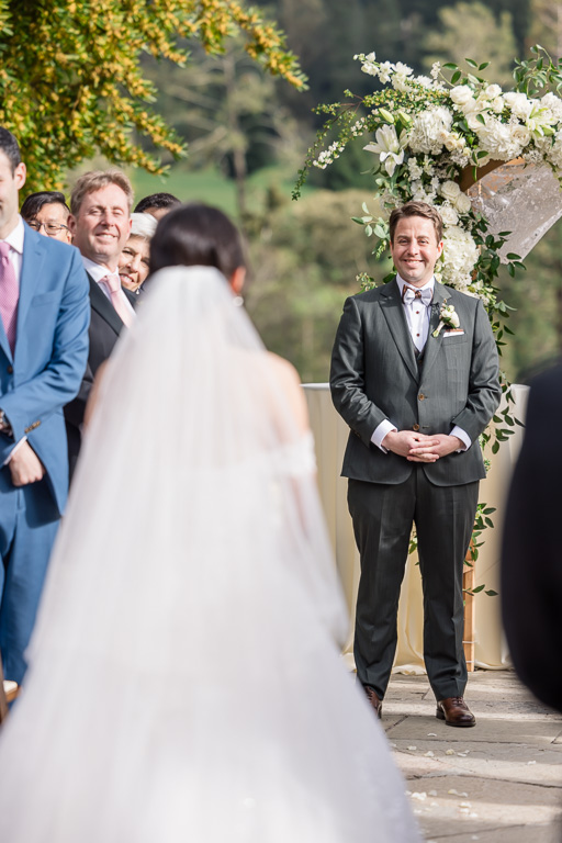 groom looking at the bride as she approaches him on the aisle