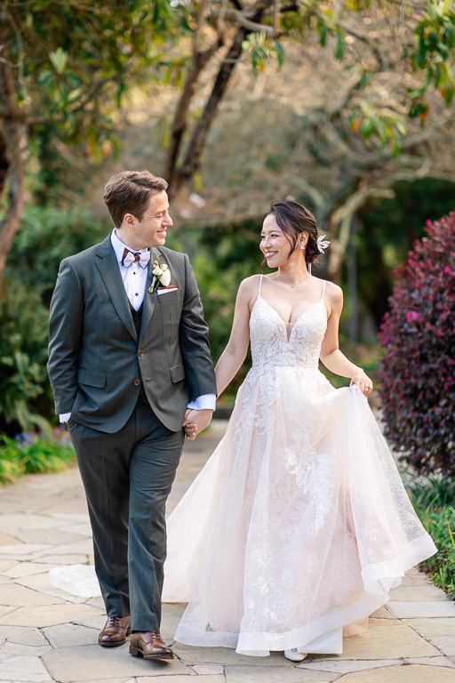 bride and groom walking along a paved path in a forest setting