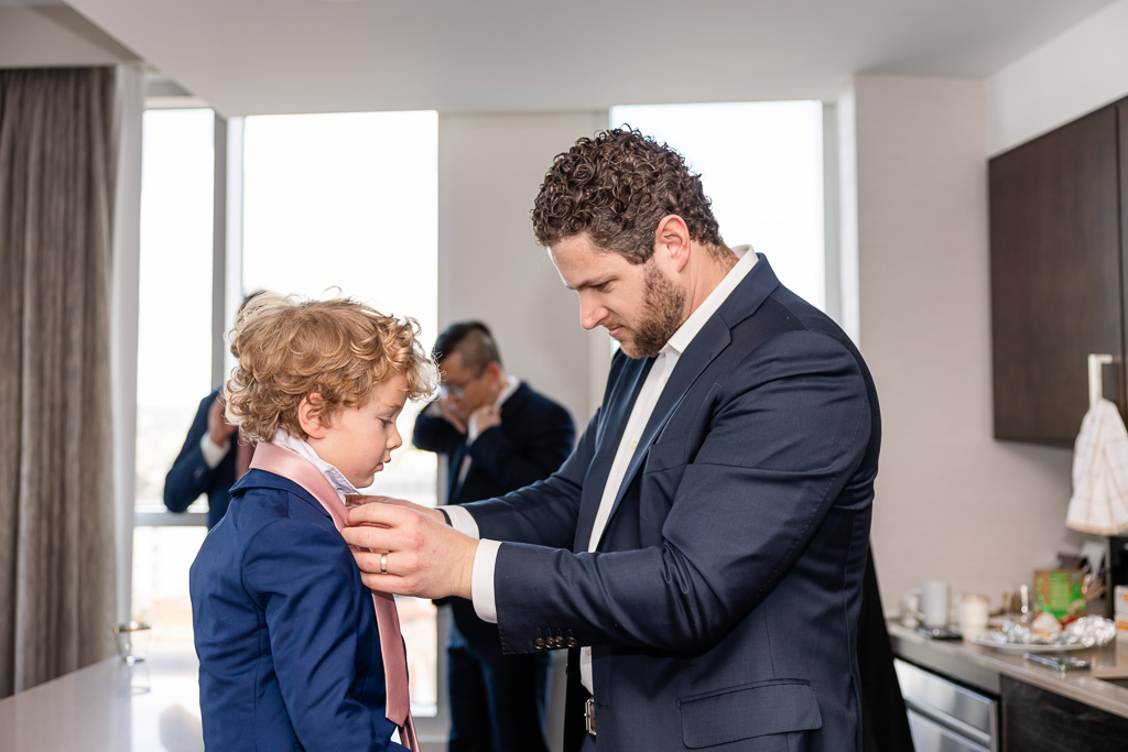 groomsman putting a tie on his son