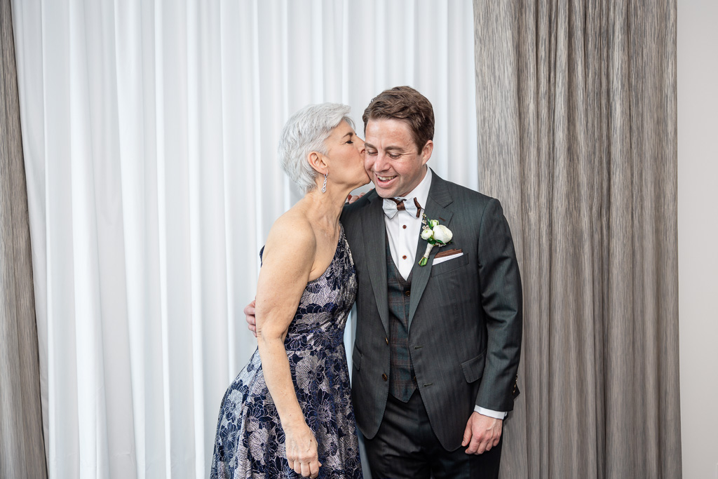 mom giving groom a kiss on the cheek