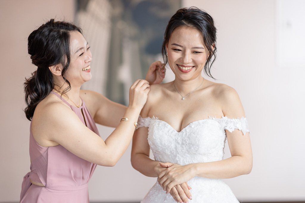 bridesmaid helping bride with jewelry