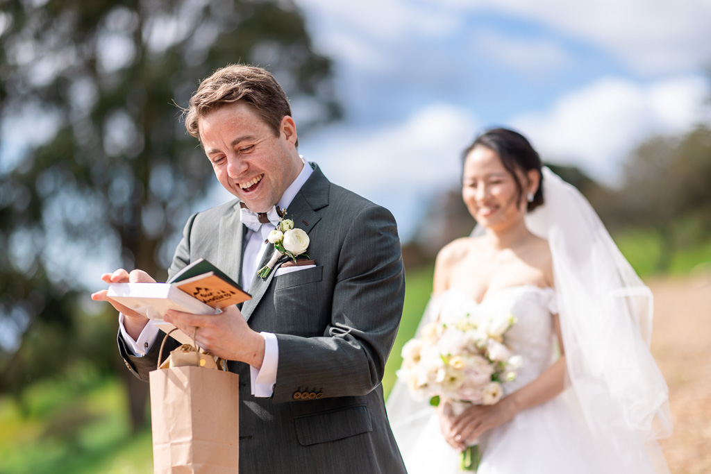 groom smiling as he flips through book given to him by bride on wedding day