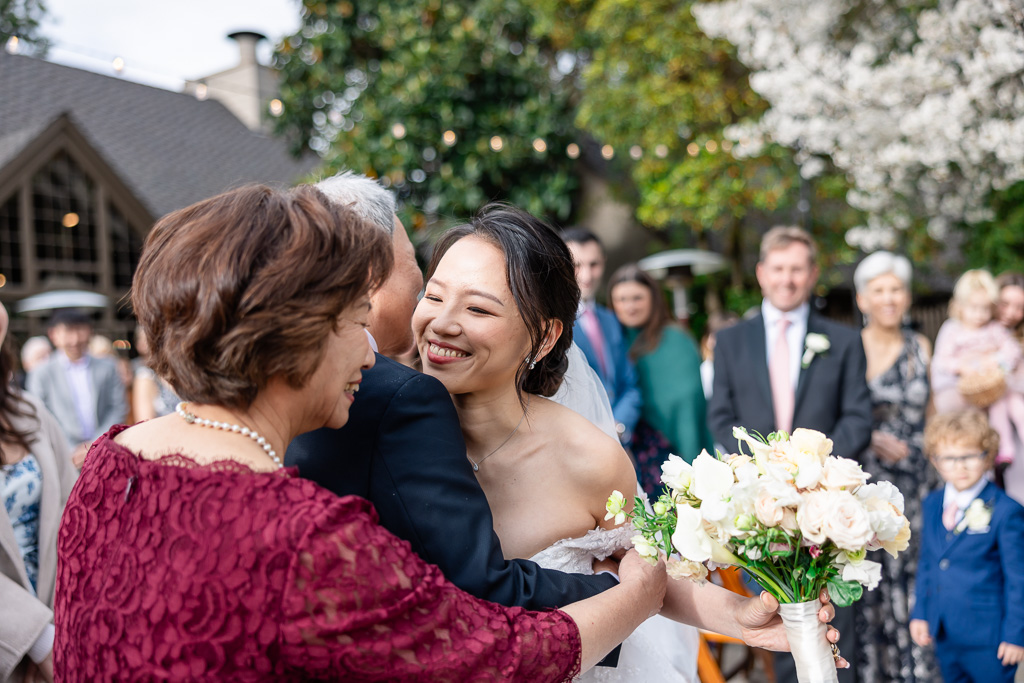 bride hugging her parents at the end of the aisle