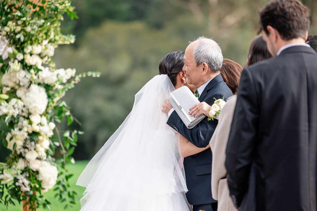 father of the bride hugging his daughter at the end of the aisle