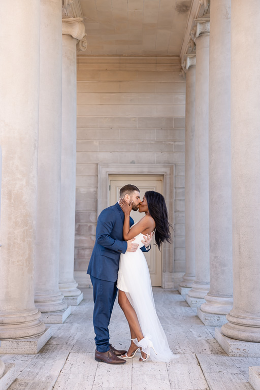 couple kissing under classical architectural columns